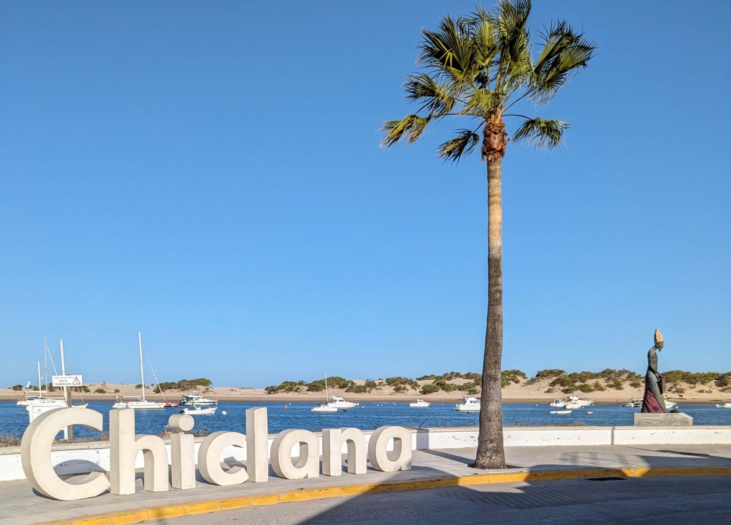 Chiclana Sign with palm tree and Melkart statue at beach